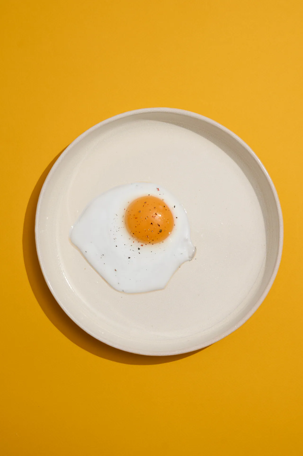 Яичница на белой тарелке, жёлтый фон